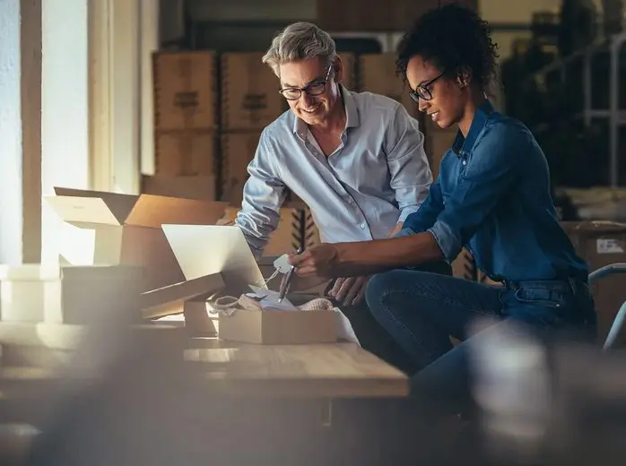 A man and woman sitting on the floor looking at papers.