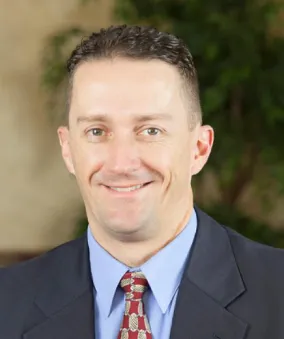 A man in a suit and tie smiling for the camera.