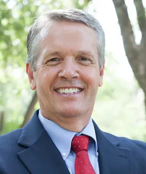 A man in a suit and tie smiling for the camera.